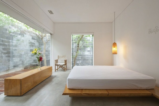 Drevená komoda, biele steny, závesná lampa pre manželskú posteľ