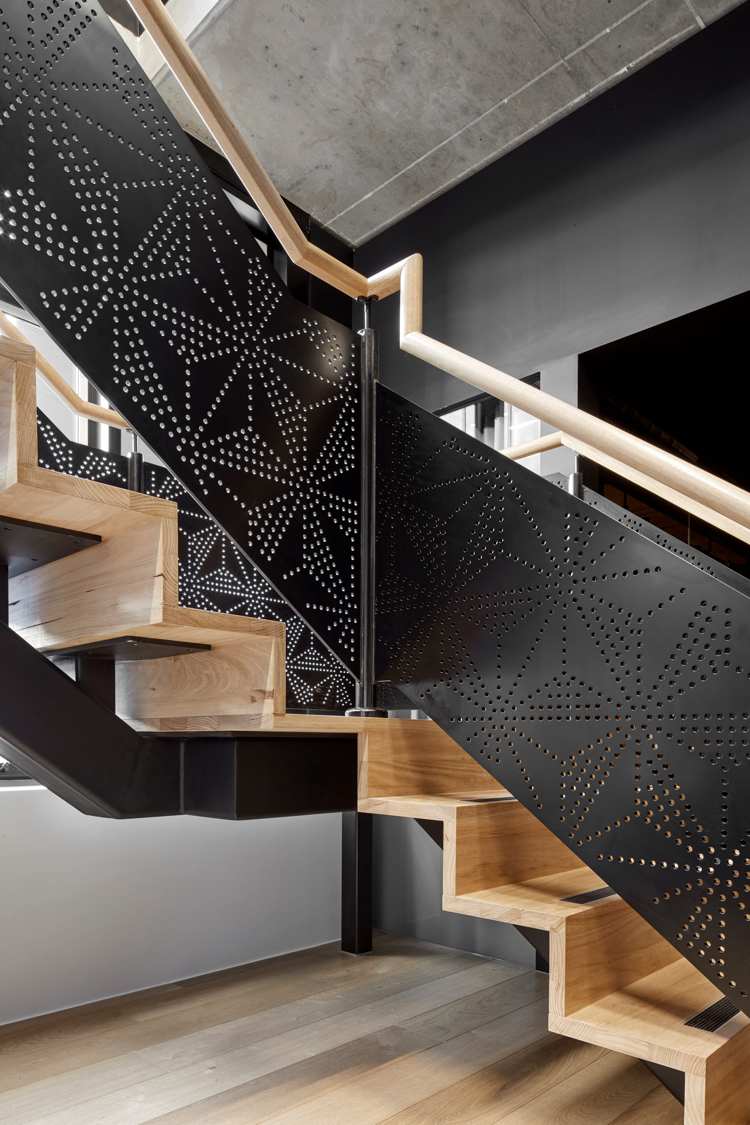 Dierované kovové zábradlie so špeciálnym vzorom čiernych drevených schodov