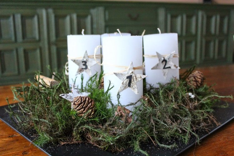 štyri biele sviečky ozdobené machom a šiškami na tanieri adventný veniec-moderné-urob si sám-mach-yapfen-tyčinky-prírodné-materiály-tanier-keryen