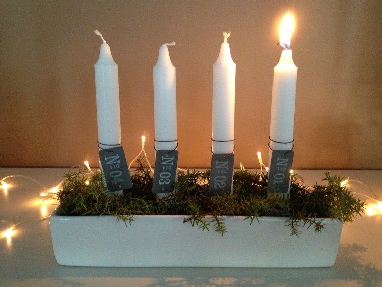 biele podlhovasté sviečky zdobené štítkami a machom adventný veniec-moderné-urob si sám-predĺžené-zdobené-sviečky-jedľa-konáre-tanier