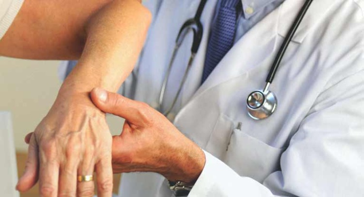 neurológ skúmajúci kĺby paží pacienta