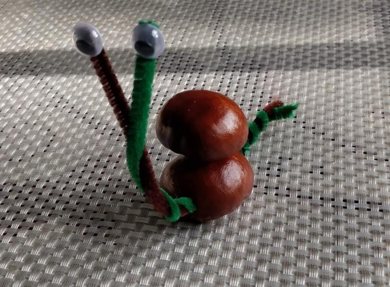 Slimák s čističom rúrok a dvoma nahromadenými gaštanmi