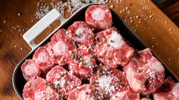 surové oxtaily posypané korením a kóšer soľou v liatinovom kastróle