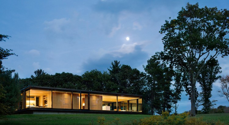 veľké obrazové okná namiesto vonkajších stien.Nočné osvetlenie v lesnej krajine