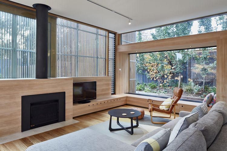 Obývacia izba prakticky zariadená krbovými kachlami, okrúhly konferenčný stolík z dreva