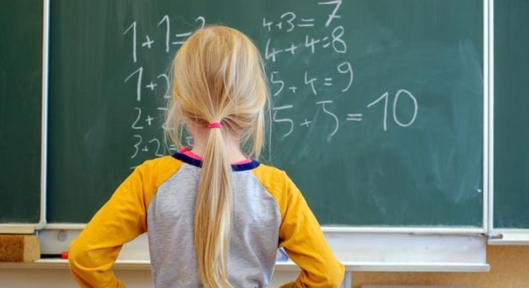 dievča stojí pred tabuľou a pokúša sa vypočítať