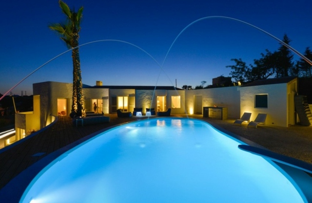 Bazénová voda má večerné biele omietnuté fasády so záhradným osvetlením