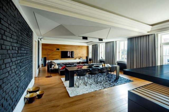 Stropný jedálenský stôl a stoličky so symetrickým vzorom v čiernej farbe znížený strop-s-trojuholníkovým vzorom-tehlová stena-v-čiernej farbe