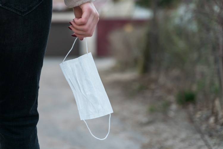 Mladá žena drží v ruke ochrannú masku proti koronavírusu