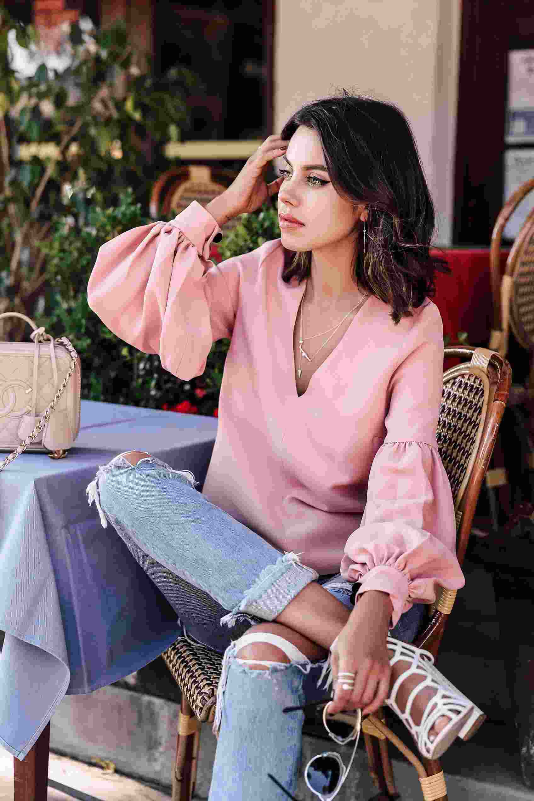 Rukávy z hodvábnej blúzky kombinujú priateľské džínsy, sandále na vysokom podpätku a ružovú kabelku