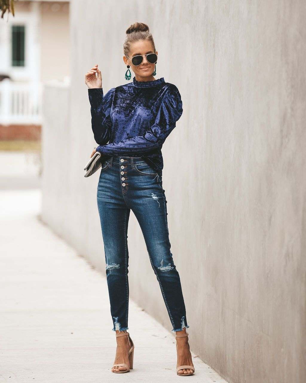 Rukávy so zamatovou blúzkou kombinujú úzke rifle s tmavomodrými sandálmi na podpätku a blond vlasmi