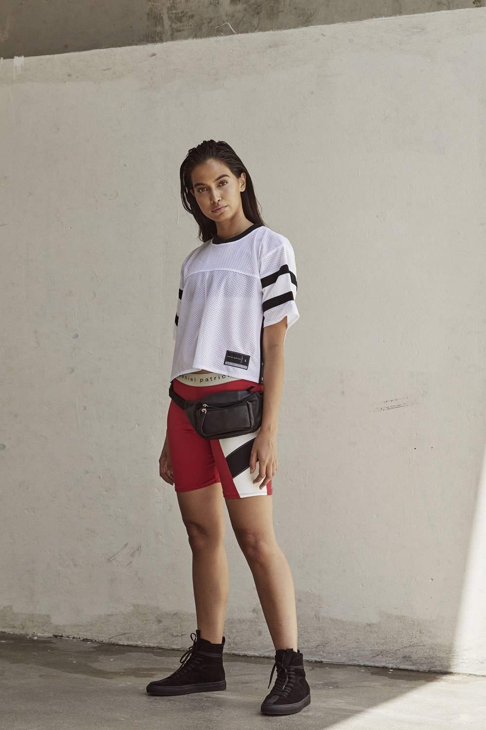 červené cyklistické šortky kombinujú športové tričko nadrozmerných vysokých tenisiek čiernej farby