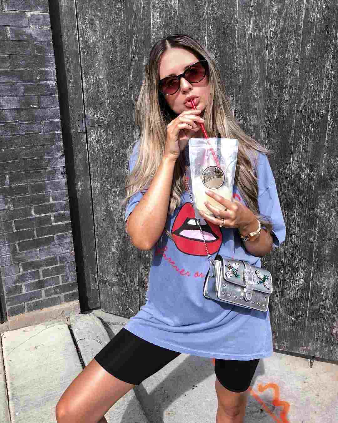 Cyklistické šortky kombinujú športové tričko fialovej nadrozmernej kabelky so striebornými blond vlasmi