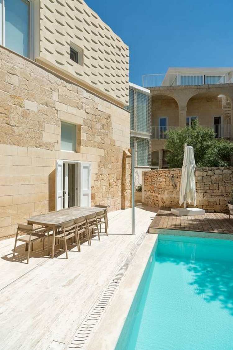 zrekonštruovaný automobilový prístrešok starej architektúry prerobený na modernú prístavbu domu s bazénom