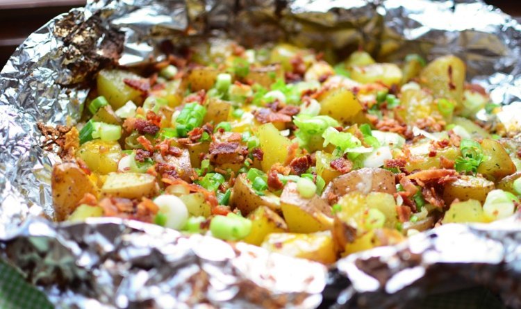 Alobalový balíček pečených zemiakov so slaninou a syrom v hliníkovej fólii v rúre
