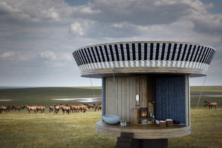 krásne zariadený okrúhly drevený dom uprostred poľa s koňmi