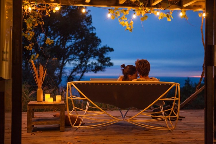 hojdacie kreslo-ležadlo v noci dvaja ľudia rámujú bielu svetelnú reťaz