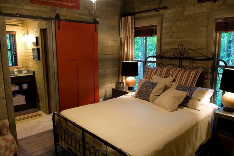 Dvere do stodoly v spálni s červeným akcentom a rustikálnymi závesmi vo vidieckom štýle