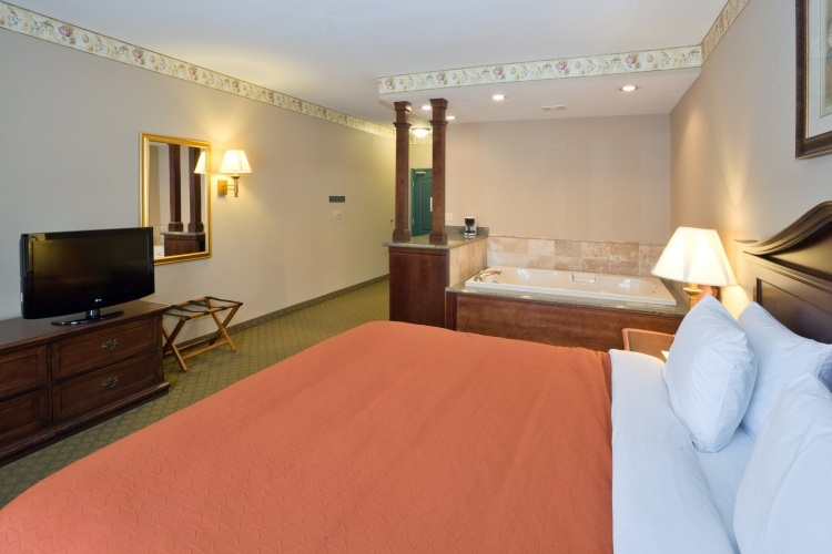 jednoduché zariadenie a dizajn spálne s vírivkou spálňa-vírivá vaňa-oranžová-prehoz na posteľ-TV-vaňa-osvetlenie-normálny-vankúš-posteľná bielizeň