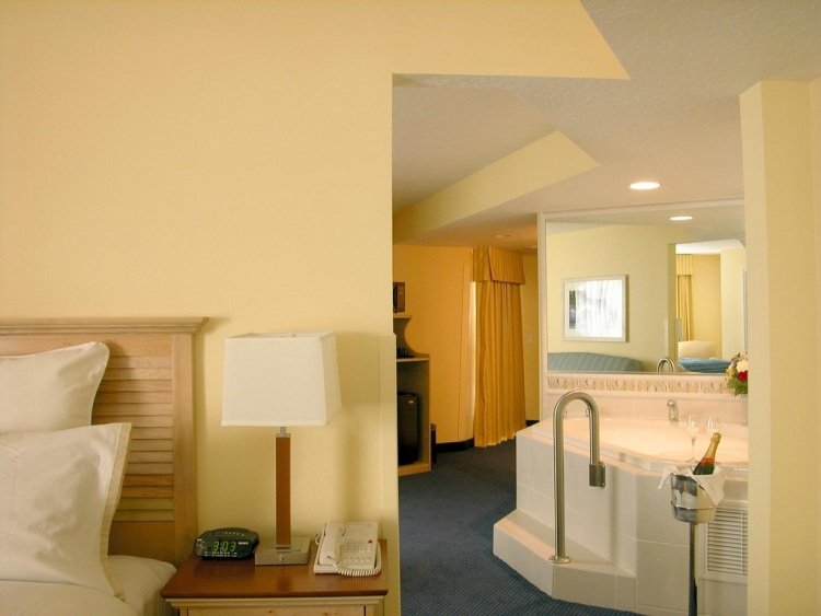 Spálňa s vírivkou v teplých farbách stien spálňa-vírivá vaňa-biela-koberce-tmavo modro-žltkastá-stena