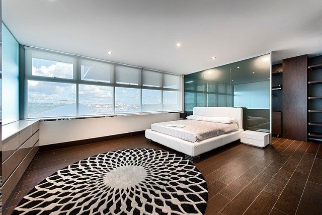 okno spálne predná podlaha dlažba drevo vzhľad biela posteľ okrúhly koberec spálňa-okno-predná-podlaha-dlažba-drevený vzhľad-biela-posteľ-okrúhly koberec