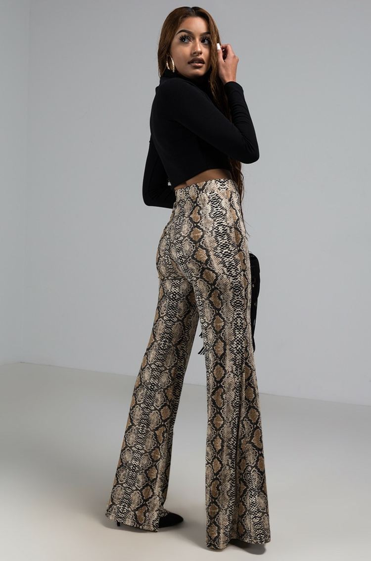 Hadí nohavice s vysokým pásom kombinujú módne trendy čiernej blúzky