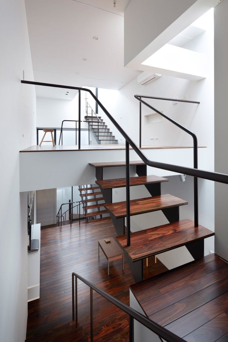 niekoľko schodov so schodmi vyrobenými z tmavého masívneho dreva praktickým spôsobom spája obytné priestory