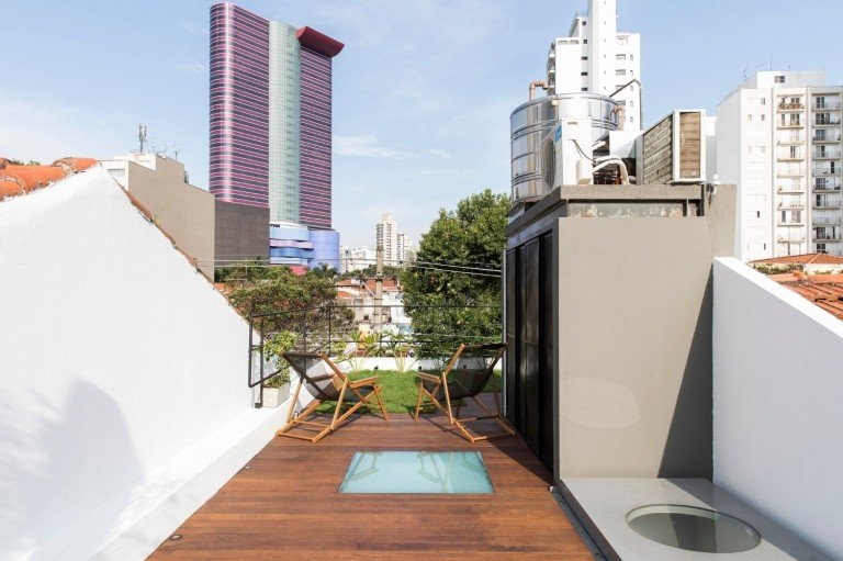 kompaktná strešná terasa s drevenou podlahou, svetlou šachtou a skladacími stoličkami s výhľadom na mesto