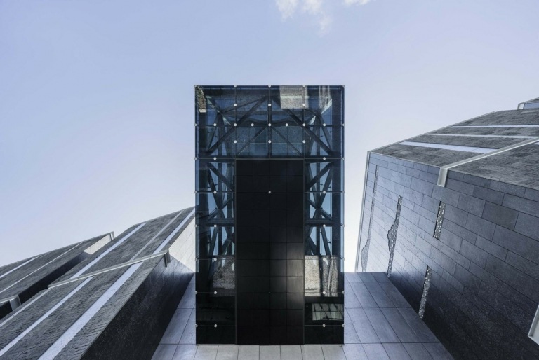 Zasklený vstupný priestor pri pohľade zospodu má čiernu čadičovú fasádu