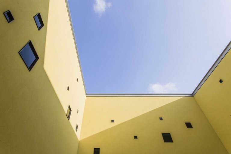 Vnútorné nádvorie so žltou fasádou a oknami rôznych veľkostí