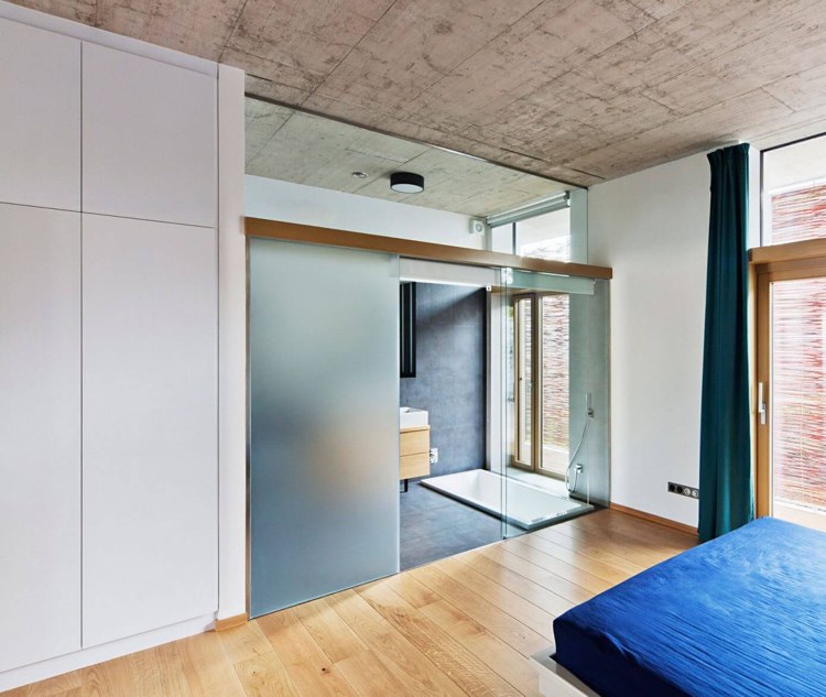 Kúpeľňa spojená so spálňou spálňa-kúpeľňa-integrovaná-sklenená-stena-prístupná-chodba podlaha