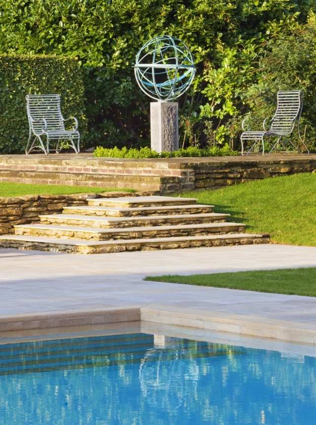 Bazén sedenie schody živý plot veľká záhradná socha dva Schodiskový živý plot veľká záhradná socha dve kovové stoličky na trávnik