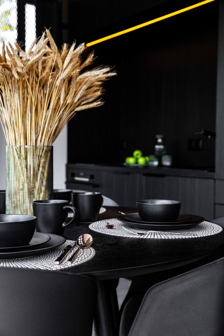 Moderná jedálenská časť zariadená čiernym dreveným stolom, ozdobou stola pšenice