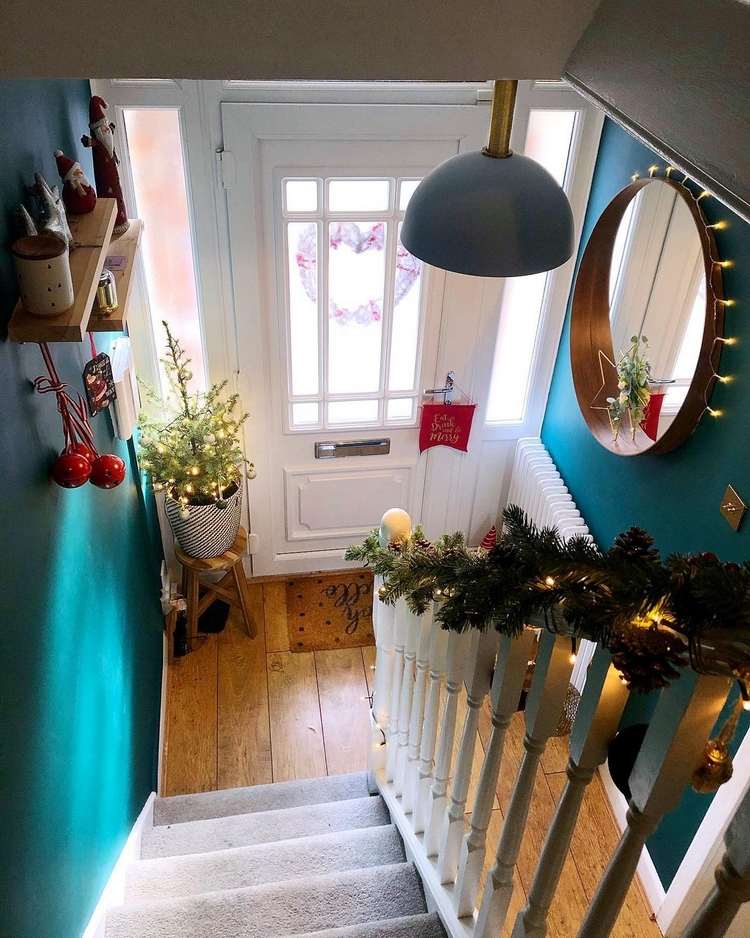 Vianočné ozdoby na schodisku. Malá jedľa v kvetináči. Jedľové girlandy a rozprávkové svetlá