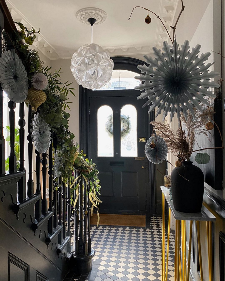 Vianočné ozdoby vo vstupnom priestore s čerstvými vetvičkami a papierovými hviezdičkami