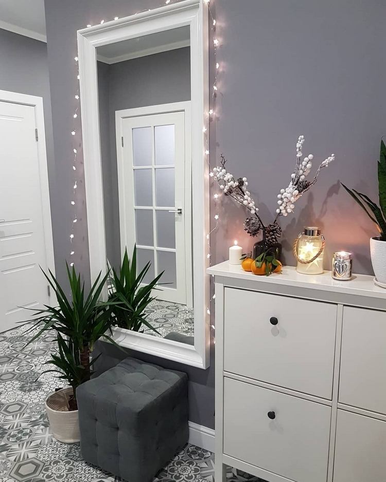 Moderné vianočné dekorácie na chodbe s LED svetelnými reťazami a bobuľovými ratolesťami na skrinke na topánky