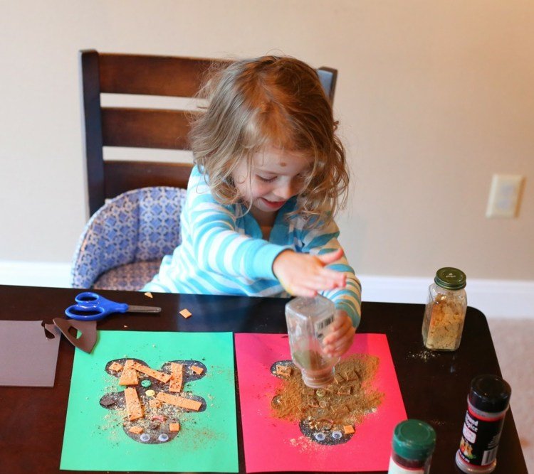 Drobní perníčky s 3 -ročnými deťmi zdobia na Vianoce škoricový papier