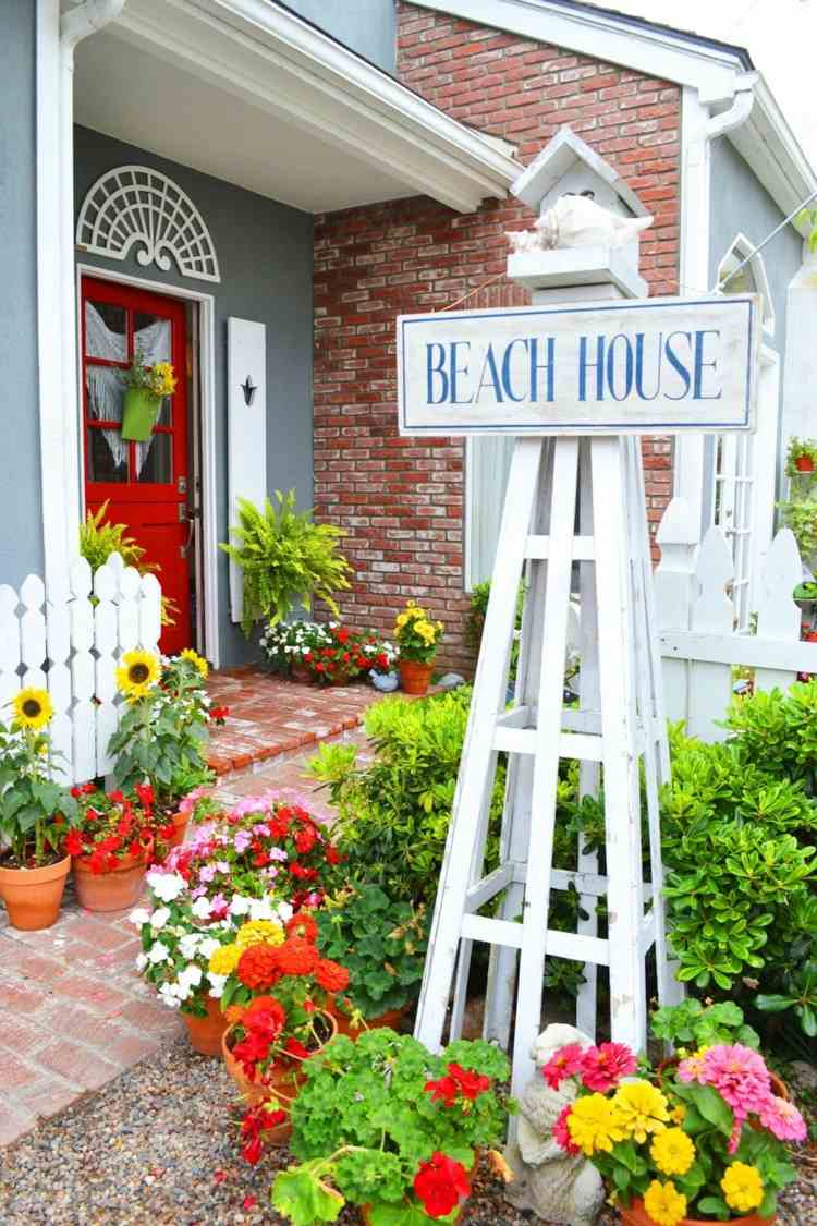 Vtáčí dom na dvore so stojanom a farebnými kvetmi v kvetináčoch