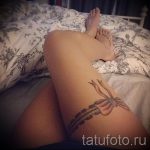 női gyönyörű tetoválás a lábán harisnyakötővel és íjjal