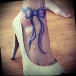 tatuaż piękny i elegancki - świąteczna kokardka na nodze dziewczyny