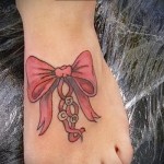 tatuaż z kokardą na nodze i literach