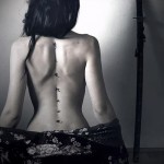 وشم على طول العمود الفقري لفتاة بأحرف صغيرة (الهيروغليفية)