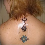 اثنان من الهيروغليفية وشوم زهرة ملونة على رقبة الفتاة الخلفية