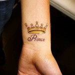 tatuaż z koroną na nadgarstku i napis PRINCE