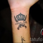 Korona tatuaż na nadgarstku z hieroglifami i skrzyżowanymi mieczami