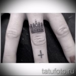 Korona tatuaż na ramieniu i krzyż na palcu