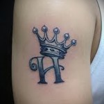 Korona tatuaż na ramieniu z inicjałem