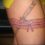 női harisnyakötő a lábán és egy kés egy rugalmas szalag alatt egy tetoválásban