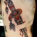 tetoválás a bordákon kés késsel, farkasfejjel díszítve