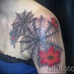 pókháló tetoválás a vállán - verzió piros virágokkal a lány testén